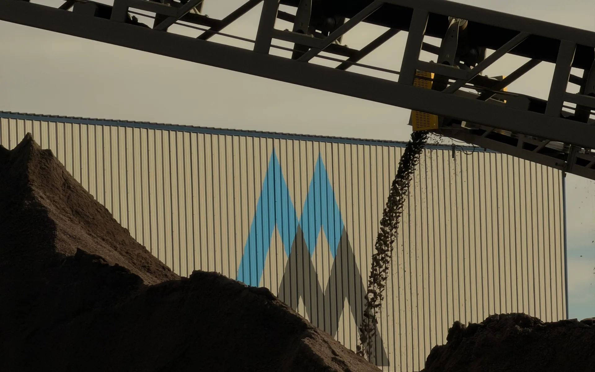 Rock falling from a stacker conveyor onto stockpiles in front of the Martin Marietta plant building at Spec Agg
